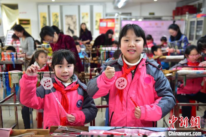 圖為小學(xué)生展示繡制好的2022年北京冬奧會吉祥物“冰墩墩”形象?！∮髟屏?攝