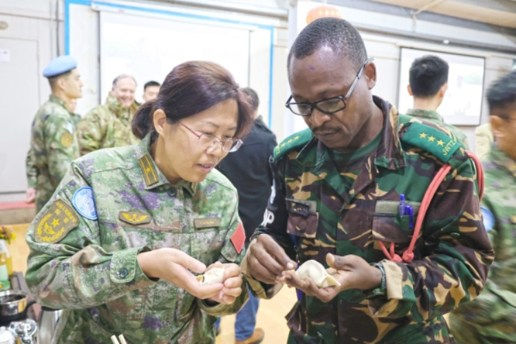 圖為維和官兵與外軍人員共同包餃子。胡光明攝