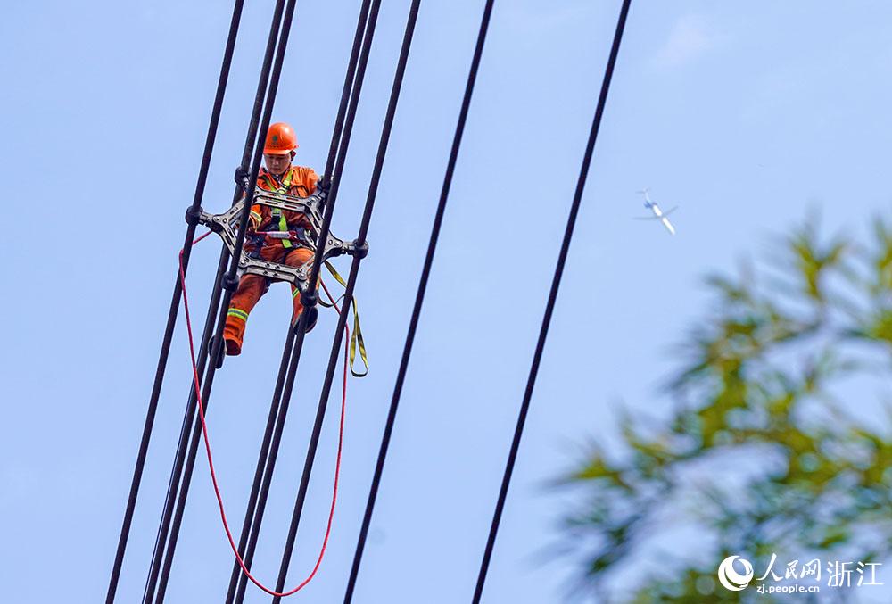 3月11日，在浙江省諸暨市河上鎮(zhèn)，浙江省送變電工程有限公司檢修人員在高空的導(dǎo)線上進(jìn)行線路檢修維護(hù)。人民網(wǎng) 章勇濤攝