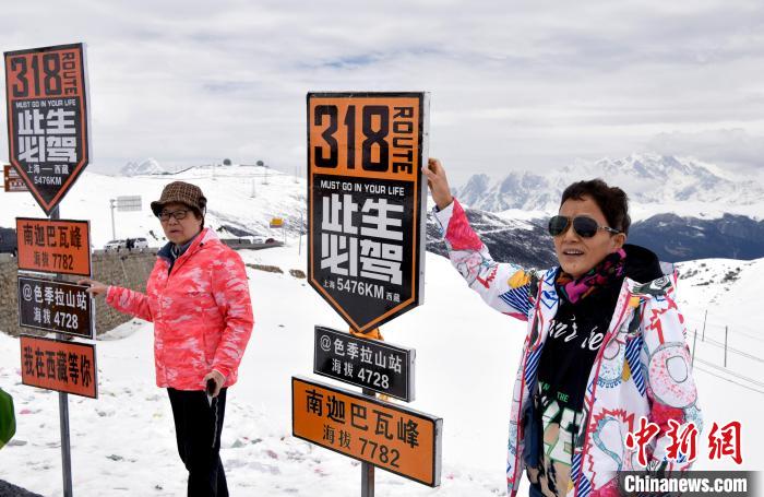 圖為5月14日，西藏林芝色季拉山觀景臺(tái)，游客與南迦巴瓦峰合影。　李林 攝