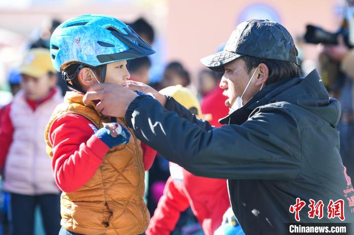 圖為拉薩市實(shí)驗(yàn)幼兒園孩子在教練的幫助下穿戴頭盔?！『闻罾?攝